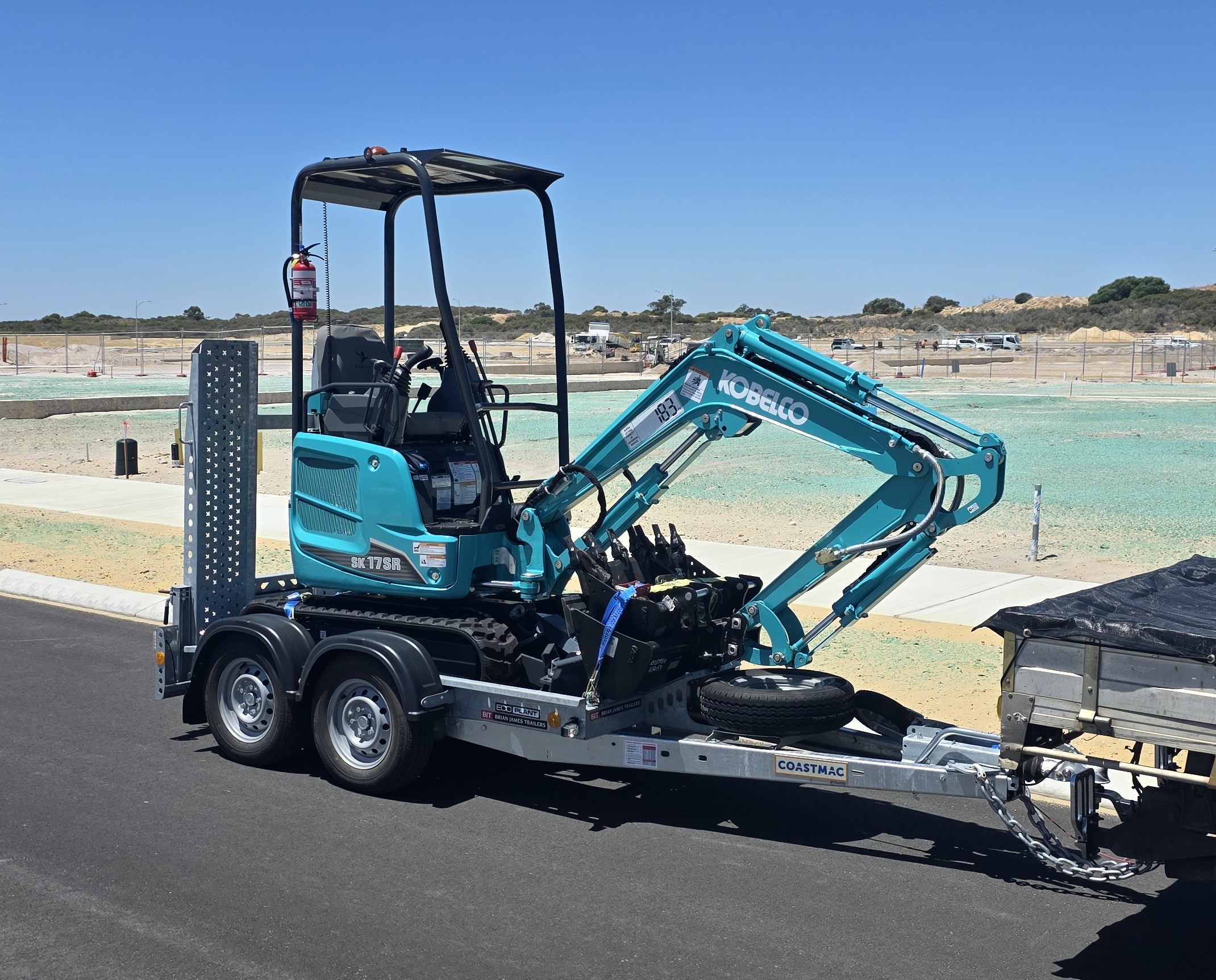 Mini excavator secured on trailer roadside/driveway